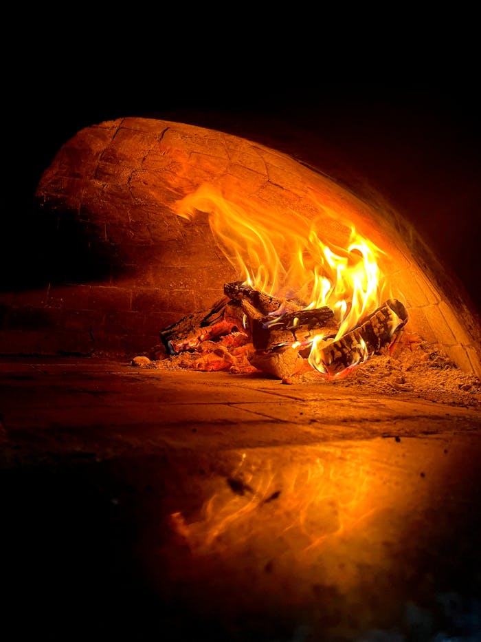 extra-programs-img A wood-fired oven with glowing flames inside, creating a warm ambiance.